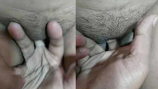 A South Asian man stimulates his partner's moist vagina with his fingers, causing her to vocalize pleasure